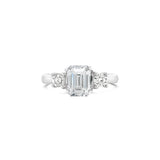 A three-stone emerald cut engagement ring with a central diamond and two smaller emeralds on either side, set in a white gold band. Sydney Engagement Ring