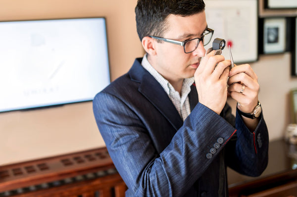 man in blue suit in a store holding a loupe to check diamond