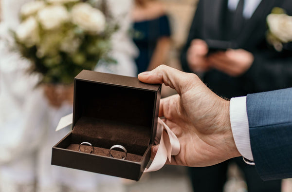 Selective focus image of best man holding box with wedding rings